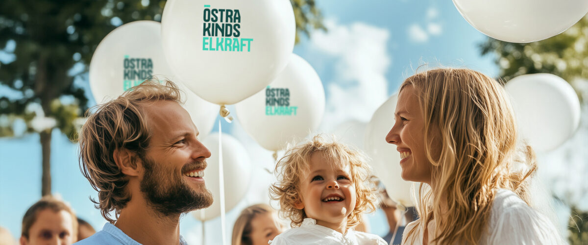 Familj med barn på utomhusevenemang med ballonger märkta Östra Kinds Elkraft.